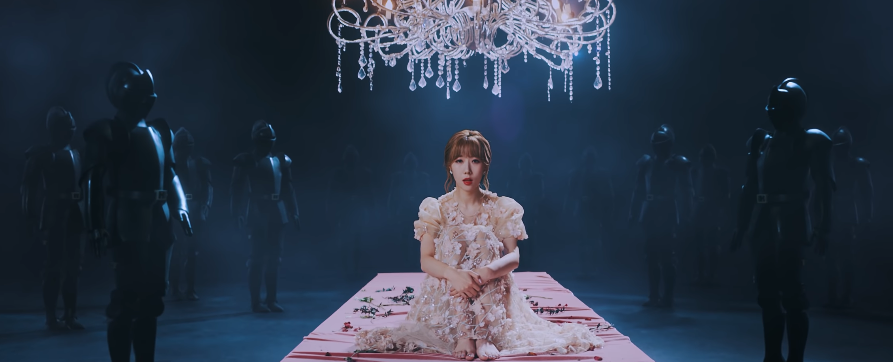 A screenshot of Handong from the Deja Vu video sitting on a dining table that is surrounded by suits of armor